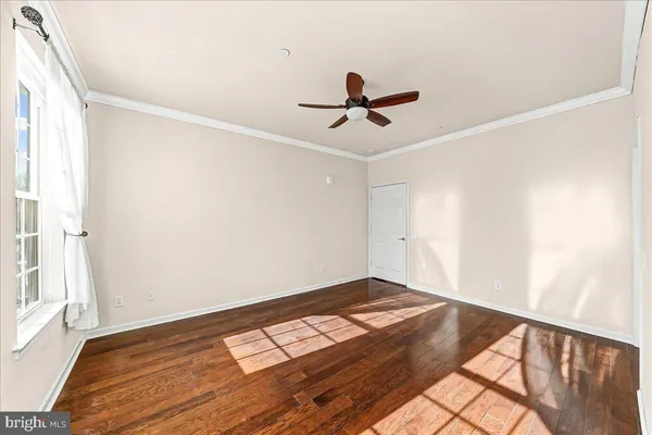 a view of empty room with wooden floor and fan