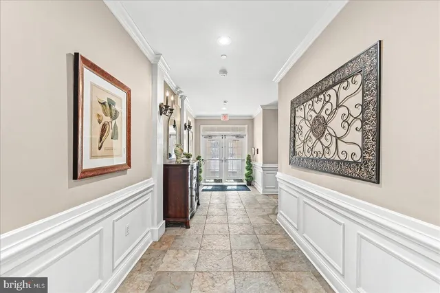 a hallway with painting on the wall and a large window