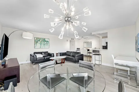 a living room with furniture a chandelier and a flat screen tv
