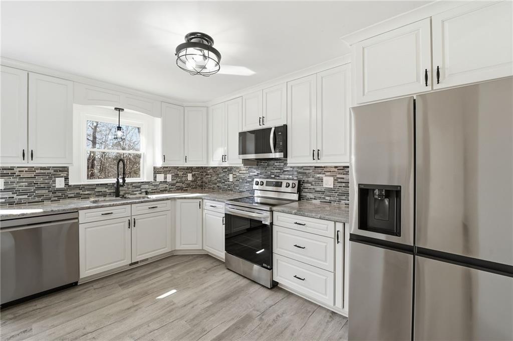 432 Barrel Way Ball Ground, GA 30107 - Photo 15 of 50 a kitchen with granite countertop white cabinets and stainless steel appliances