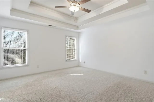 an empty room with windows and chandelier fan