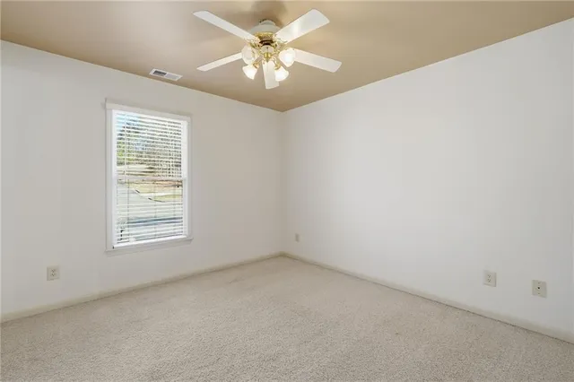 an empty room with windows and ceiling fan