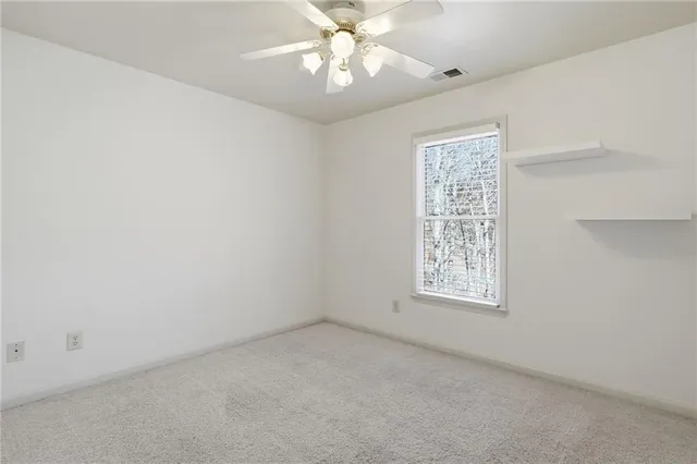 an empty room with a window and a fan
