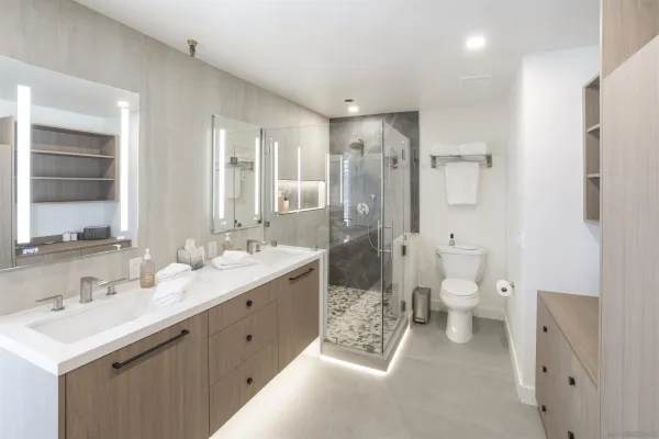 a bathroom with a double vanity sink toilet mirror and windows