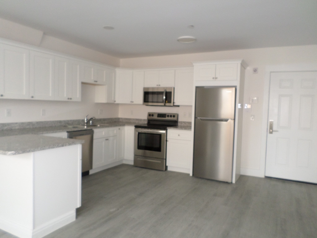 267 Broadway Chelsea, MA 02150 - Photo 15 of 30 a kitchen with a refrigerator sink and white cabinets