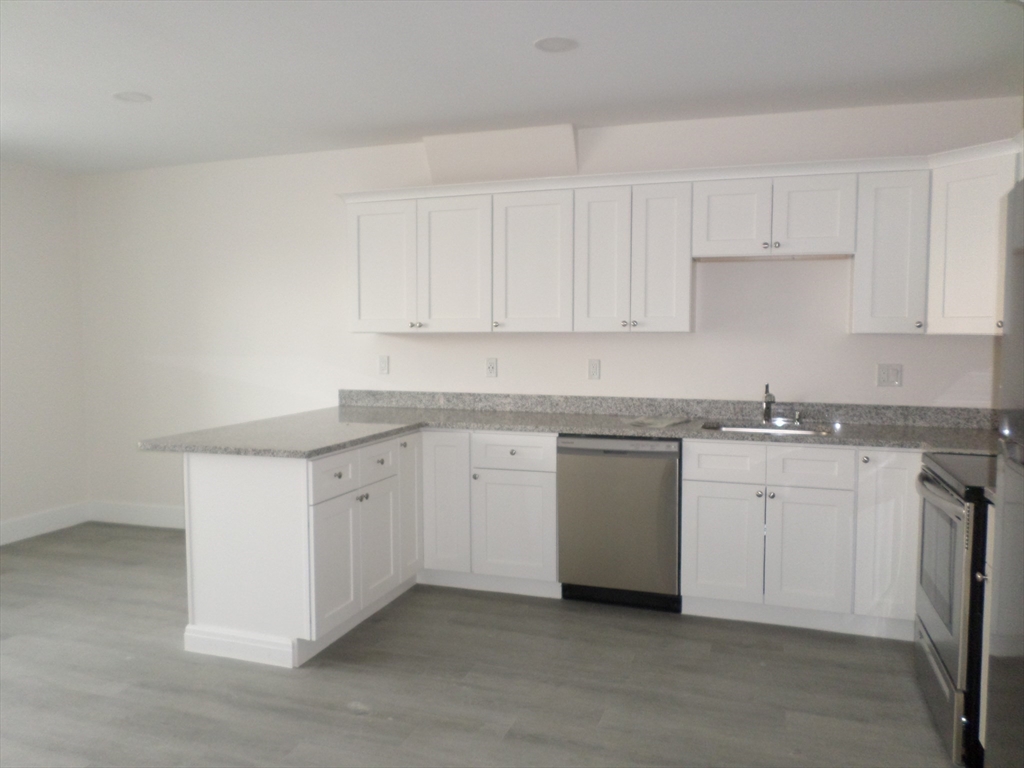 267 Broadway Chelsea, MA 02150 - Photo 7 of 30 a kitchen with granite countertop white cabinets and white appliances