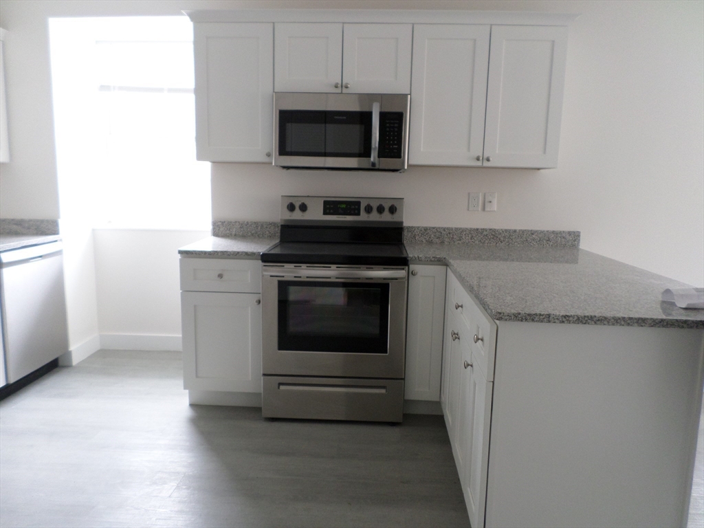 267 Broadway Chelsea, MA 02150 - Photo 8 of 30 a kitchen with granite countertop white cabinets and stainless steel appliances