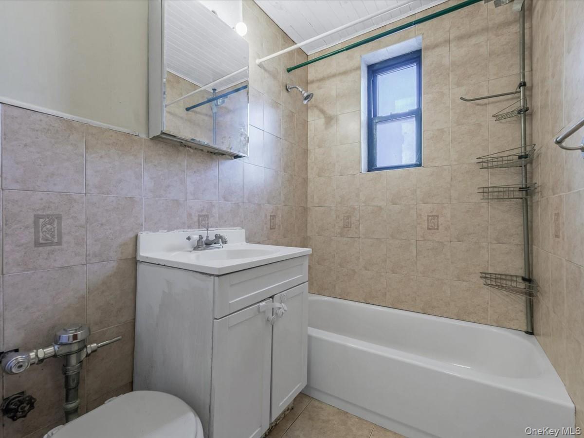 44-05 Macnish Street, Unit 1B Queens, NY 11373 - Photo 12 of 13 Bathroom with vanity, tile walls, tub / shower combination, and light tile patterned flooring