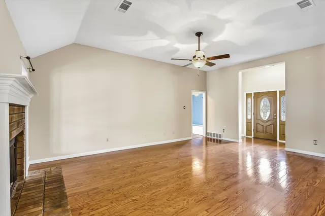 a view of an empty room with window and wooden floor