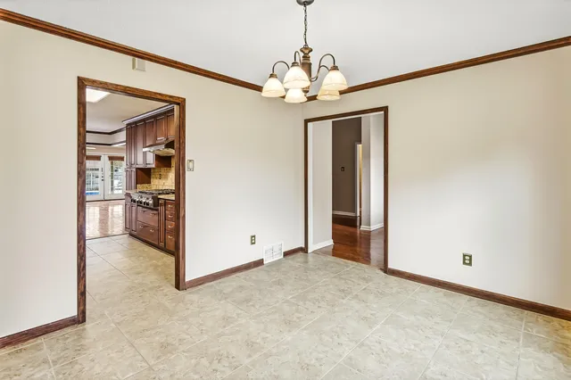 a view of a livingroom with a chandelier fan and kitchen view