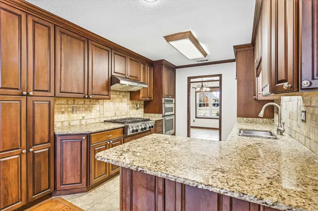 a kitchen with stainless steel appliances granite countertop a stove sink and cabinets