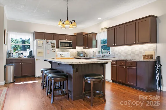 a kitchen with kitchen island granite countertop a sink stove and refrigerator