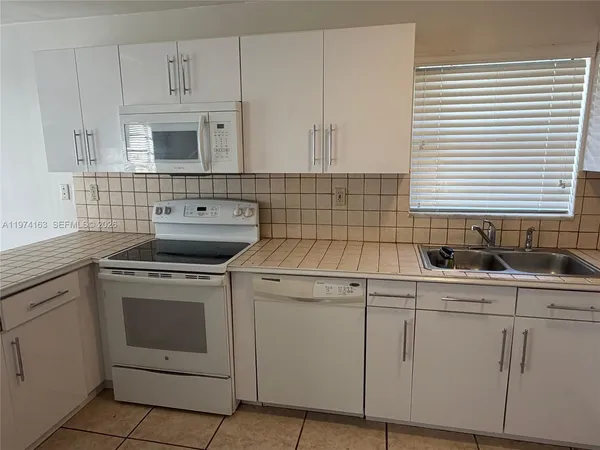 a kitchen with cabinets appliances a sink and a window