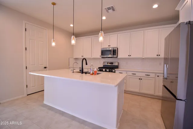 a kitchen with kitchen island a sink a stove a refrigerator and cabinets