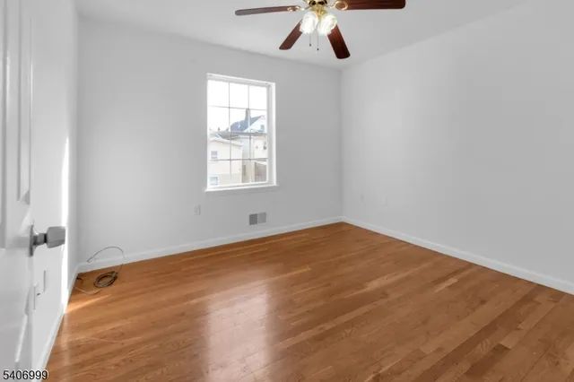 an empty room with a chandelier fan and windows