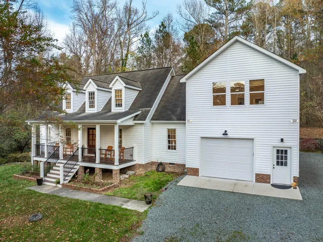 a view of a house with a yard and lawn chairs with a large tree