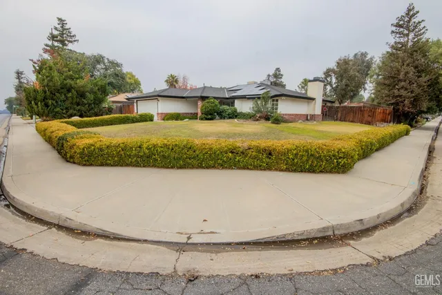 a view of an house with backyard and bushes