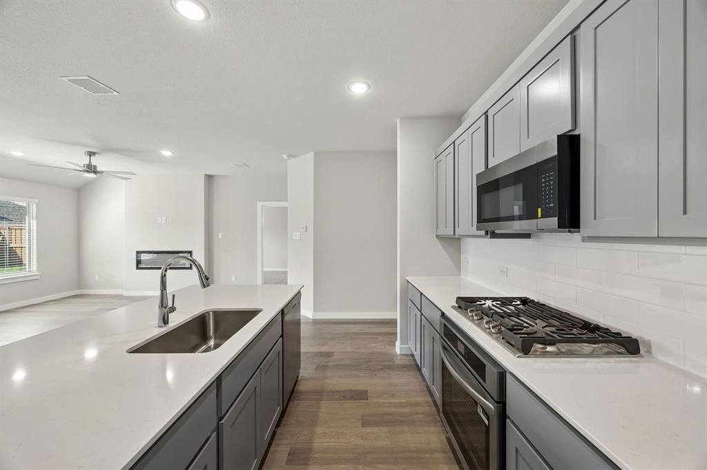1441 Companero Street Haslet, TX 76052 - Photo 7 of 33 a kitchen with stainless steel appliances kitchen island a stove a sink and a microwave
