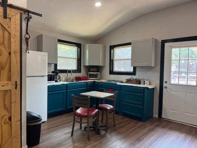 429 County Road 1191 Kopperl, TX 76652 - Photo 7 of 30 Kitchen featuring a barn door, blue cabinets, light countertops, dark wood-type flooring, and vaulted ceiling