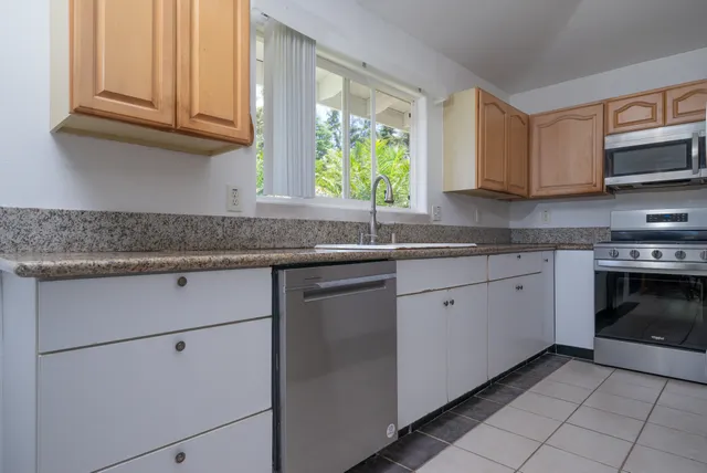 a kitchen with granite countertop stainless steel appliances white cabinets granite counter tops and a window