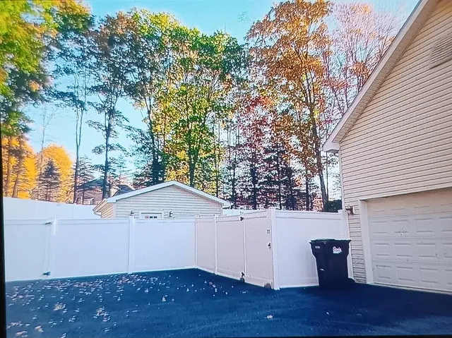 a view of a small space in front of a house with wooden fence
