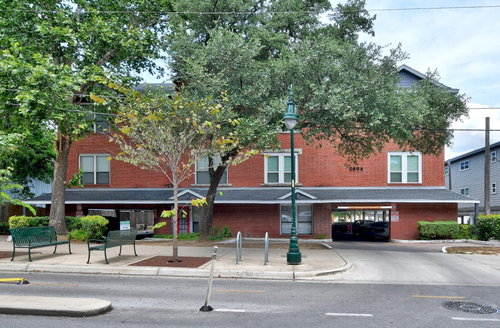 2804 Rio Grande Street, Unit 310 Austin, TX 78705 - Photo 20 of 22 A classic red brick building features a convenient integrated garage and vibrant street-level landscaping.