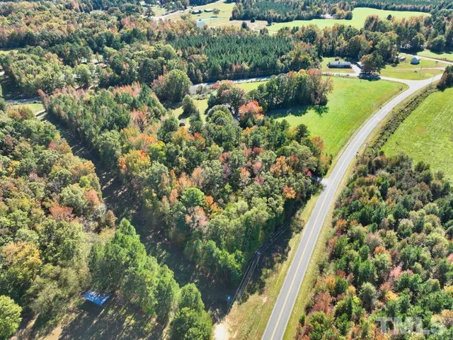 an aerial view of residential house with outdoor space and trees all around