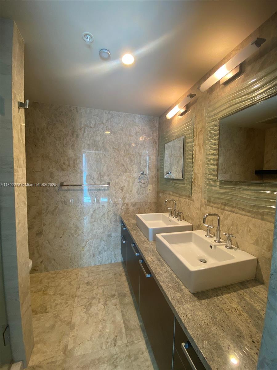 185 Southwest 7th Street, Unit 2312 Miami, FL 33130 - Photo 21 of 32 a bathroom with a granite countertop sink a mirror and a shower
