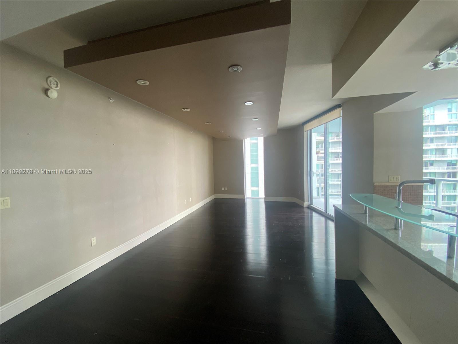 185 Southwest 7th Street, Unit 2312 Miami, FL 33130 - Photo 10 of 32 an empty room with wooden floor and windows with curtains