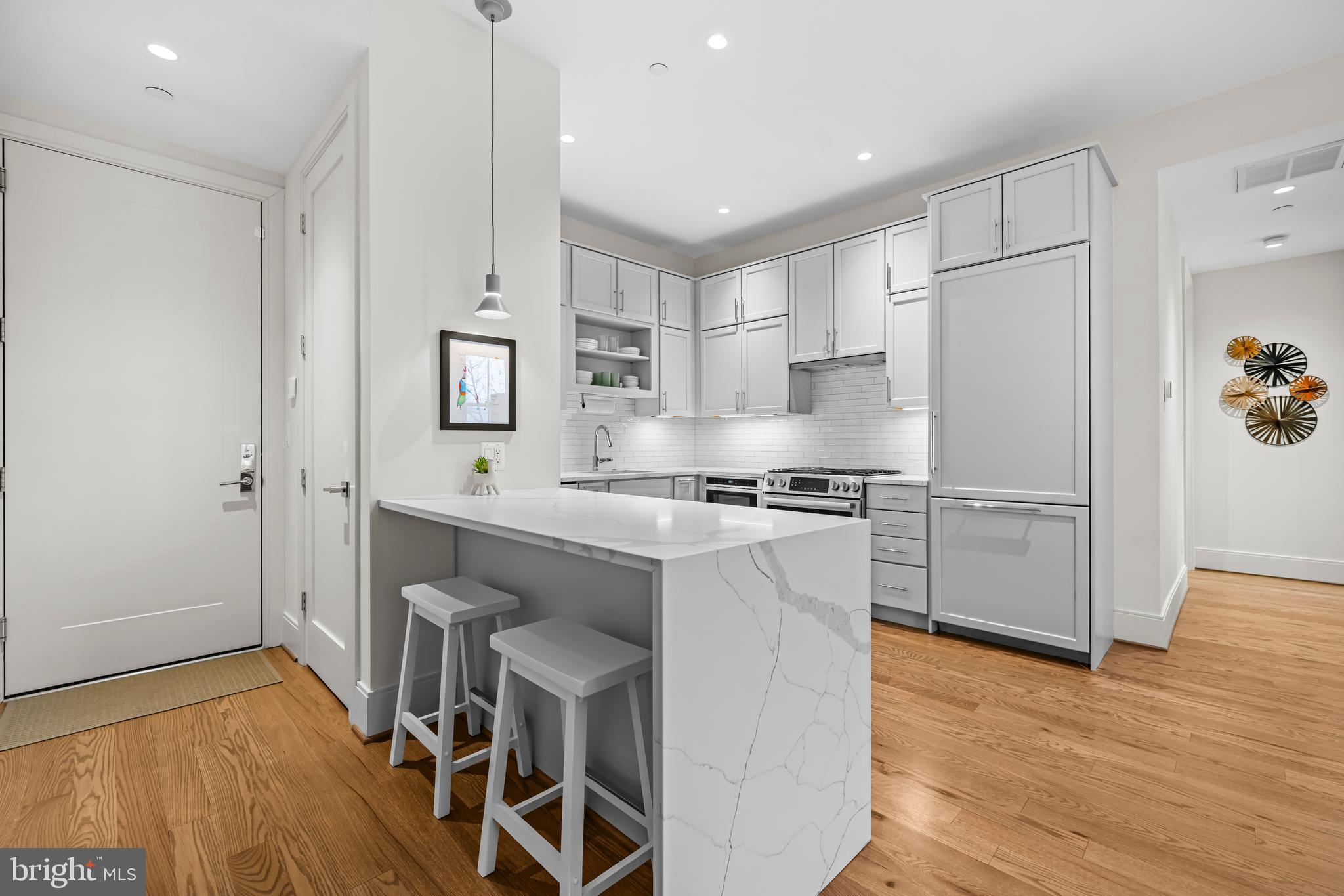 270 15th Street Southeast, Unit 301 Washington, DC 20003 - Photo 12 of 31 a kitchen with granite countertop a refrigerator stove a sink and white cabinets with wooden floor