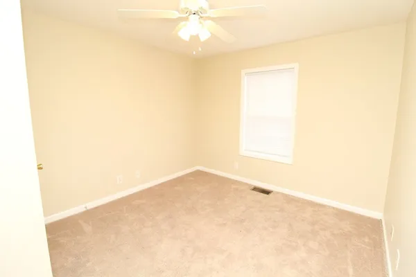 an empty room with a ceiling fan and a window