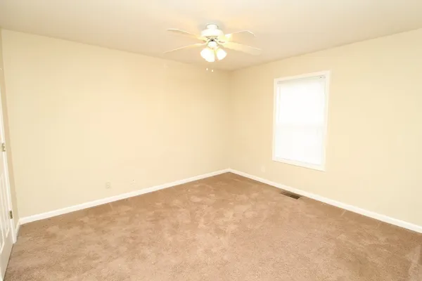 an empty room with a ceiling fan and a window