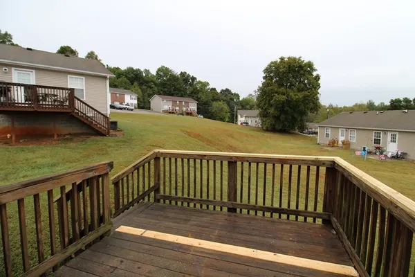 a view of a wooden deck and a yard with swimming pool