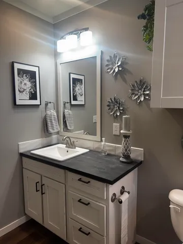 a bathroom with a granite countertop toilet sink and mirror