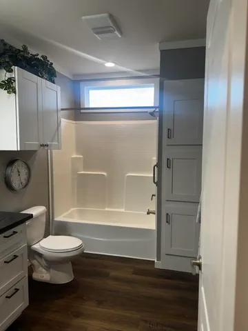 a view of an empty room with wooden floor and cabinets