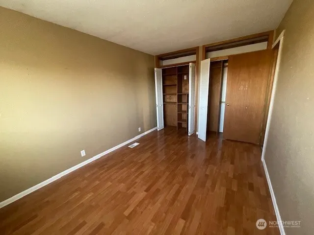an empty room with wooden floor and entrance