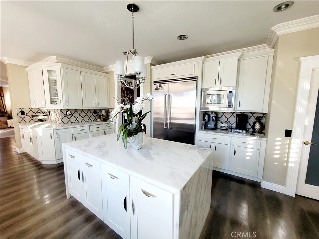 14119 Ashton Lane Riverside, CA 92508 - Photo 27 of 47 a kitchen with stainless steel appliances kitchen island granite countertop a refrigerator a stove a sink and white cabinets with wooden floor