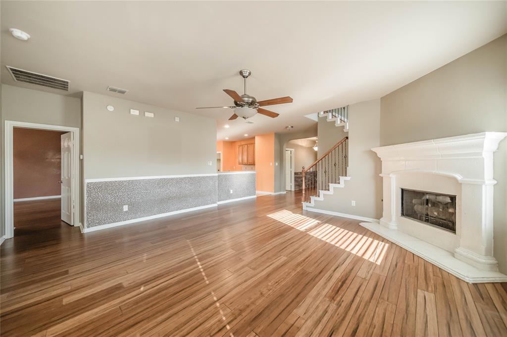 1117 Baylor Road Melissa, TX 75454 - Photo 18 of 40 a view of a livingroom with wooden floor a ceiling fan a fireplace and windows