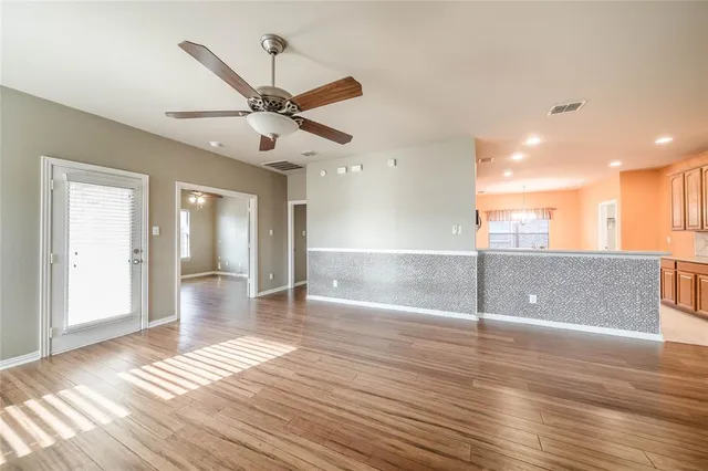 a view of empty room with wooden floor and fan