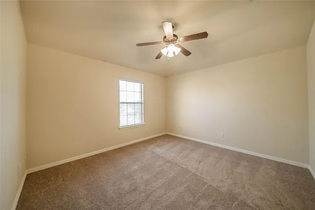 a view of an empty room with chandelier fan and a window