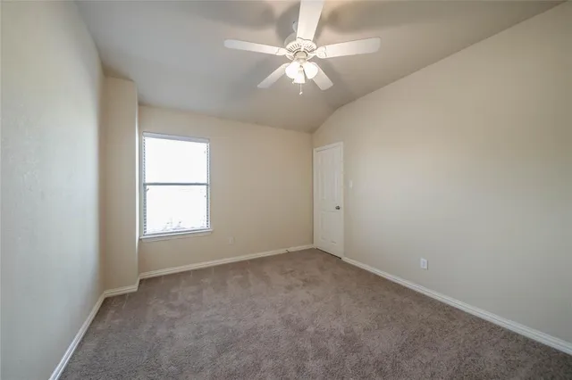an empty room with a chandelier fan and windows