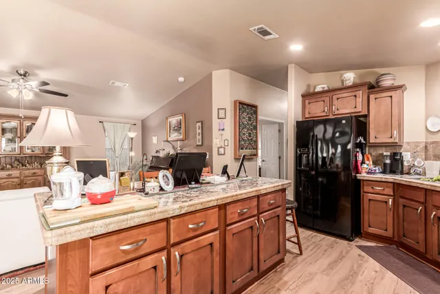 a kitchen with stainless steel appliances kitchen island granite countertop a refrigerator and cabinets