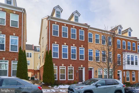 a front view of a building with lot of cars and trees