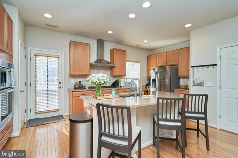 a kitchen with stainless steel appliances granite countertop a stove a refrigerator a dining table and chairs