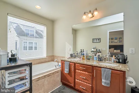 a bathroom with a granite countertop sink mirror bathtub and double