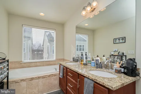 a bathroom with a granite countertop sink a large mirror and a bathtub