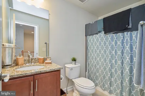 a bathroom with a granite countertop sink a toilet and a mirror