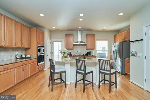 a kitchen with stainless steel appliances a dining table chairs refrigerator and cabinets