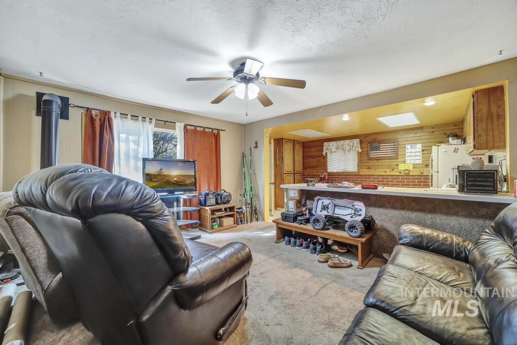 111 2nd Street Rupert, ID 83350 - Photo 22 of 45 Living area featuring a floor-to-ceiling stovepipe, ceiling fan, and carpeted flooring