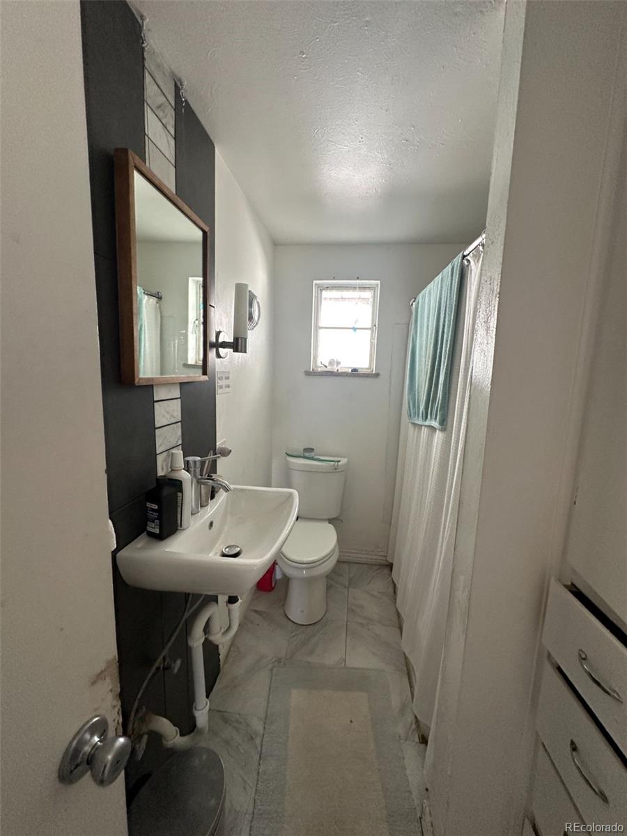 1265 Yates Street Denver, CO 80204 - Photo 13 of 17 a bathroom with a sink a toilet and a mirror